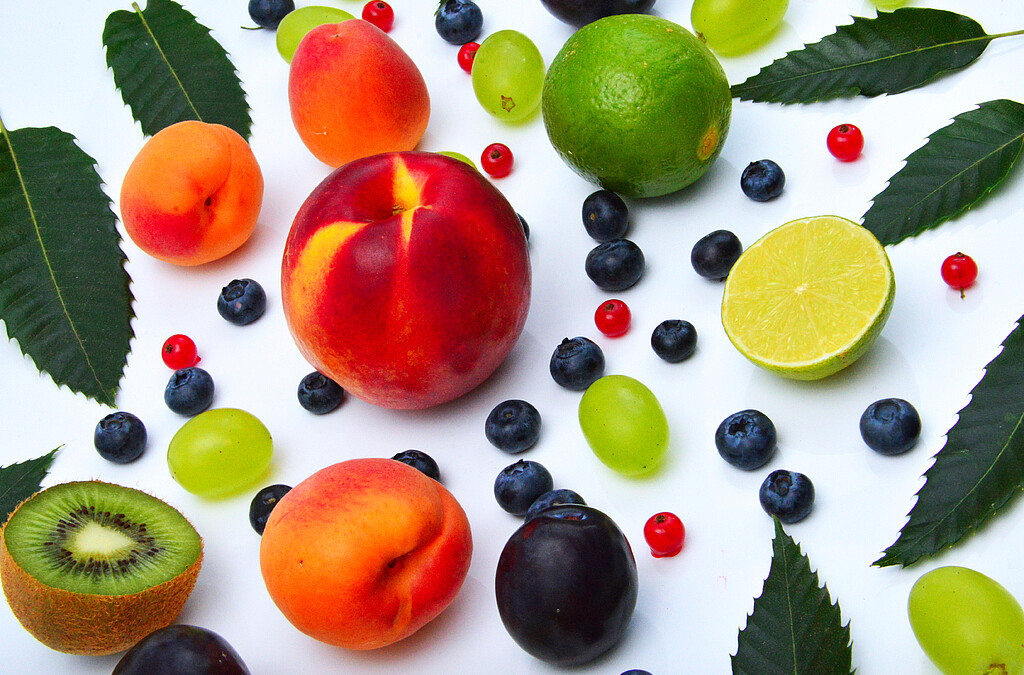 Eine bunte Auswahl an frischem Obst: Kiwi, Pfirsich, Aprikose, Zitrone